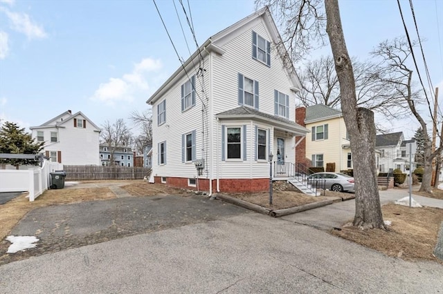 traditional style home with aphalt driveway, fence, and a residential view