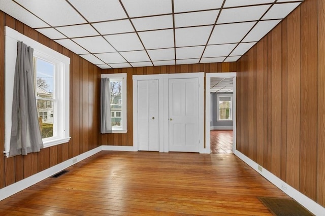 interior space featuring baseboards, visible vents, wooden walls, and light wood finished floors