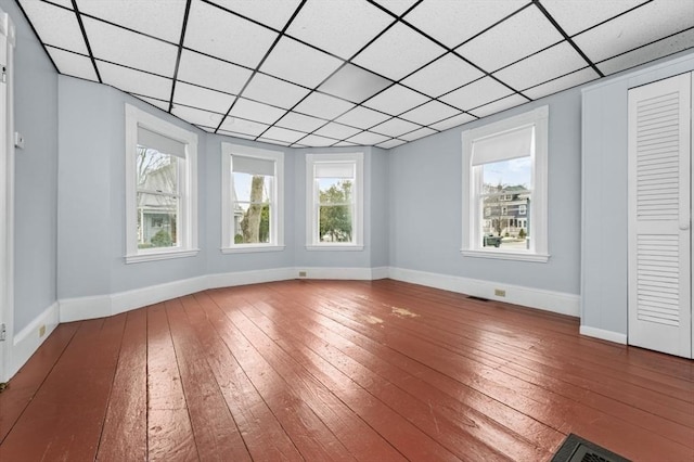 interior space featuring hardwood / wood-style floors, a paneled ceiling, and baseboards