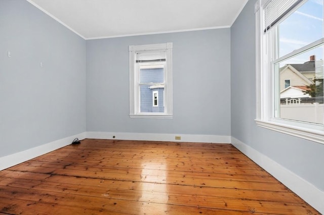 empty room featuring ornamental molding, baseboards, and hardwood / wood-style flooring