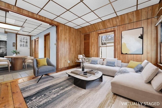 living area featuring a drop ceiling, wood finished floors, and wooden walls