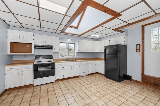 kitchen with white dishwasher, under cabinet range hood, range with electric cooktop, a sink, and freestanding refrigerator