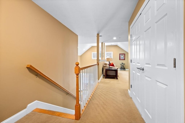 hall featuring baseboards, an upstairs landing, carpet flooring, and vaulted ceiling