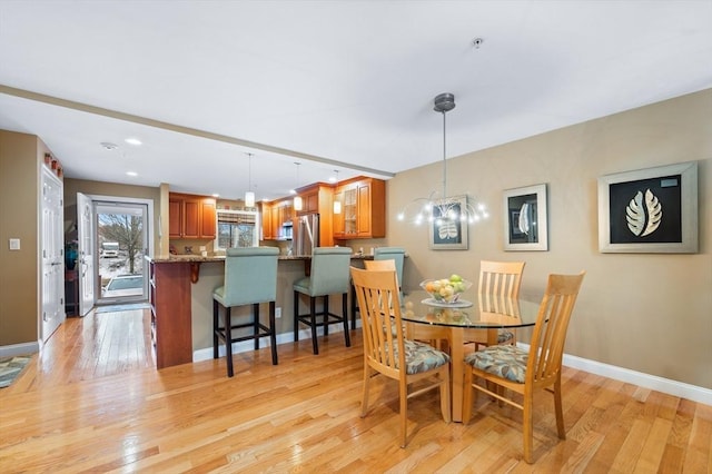 dining space featuring light wood finished floors, recessed lighting, an inviting chandelier, and baseboards