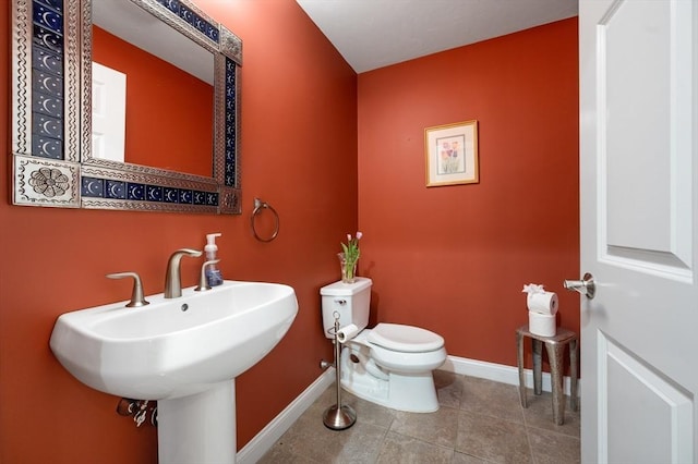 bathroom featuring a sink, baseboards, toilet, and tile patterned flooring