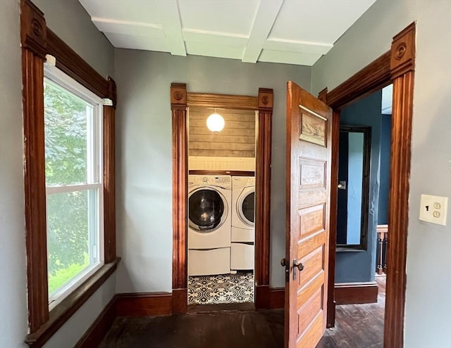 clothes washing area with baseboards, washing machine and dryer, and a healthy amount of sunlight