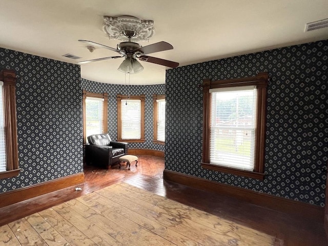 interior space with a healthy amount of sunlight, wallpapered walls, visible vents, and hardwood / wood-style flooring