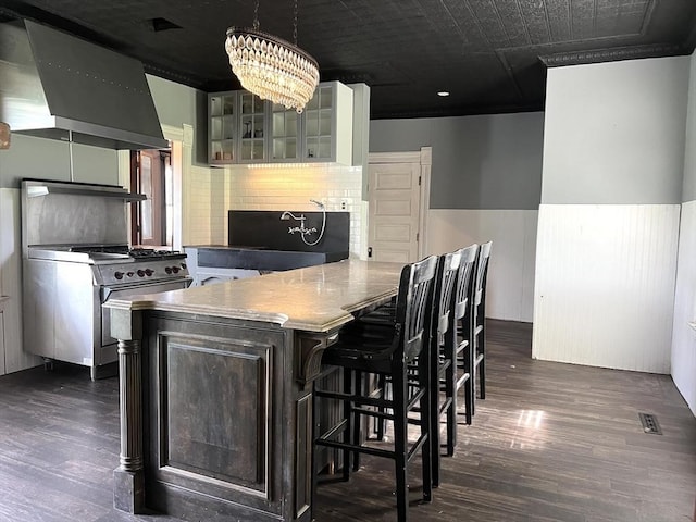 kitchen with dark wood-style floors, wall chimney range hood, glass insert cabinets, and high end range