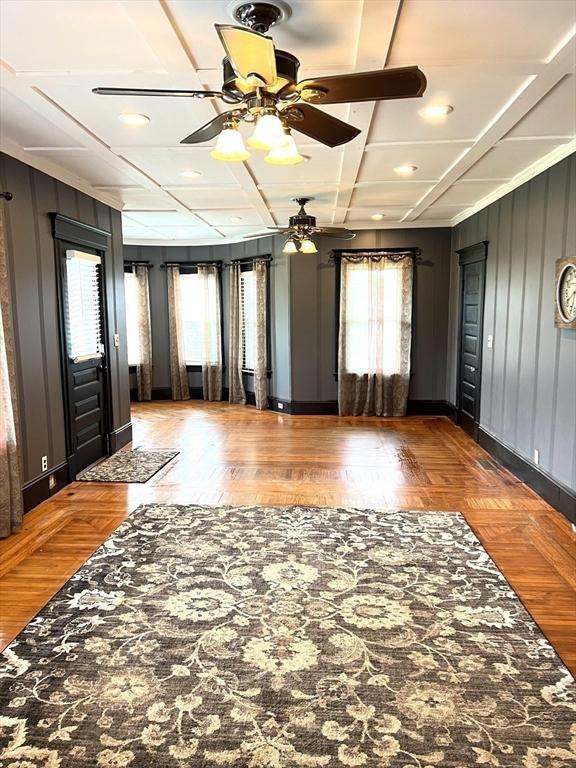 interior space featuring coffered ceiling, beam ceiling, and wooden walls