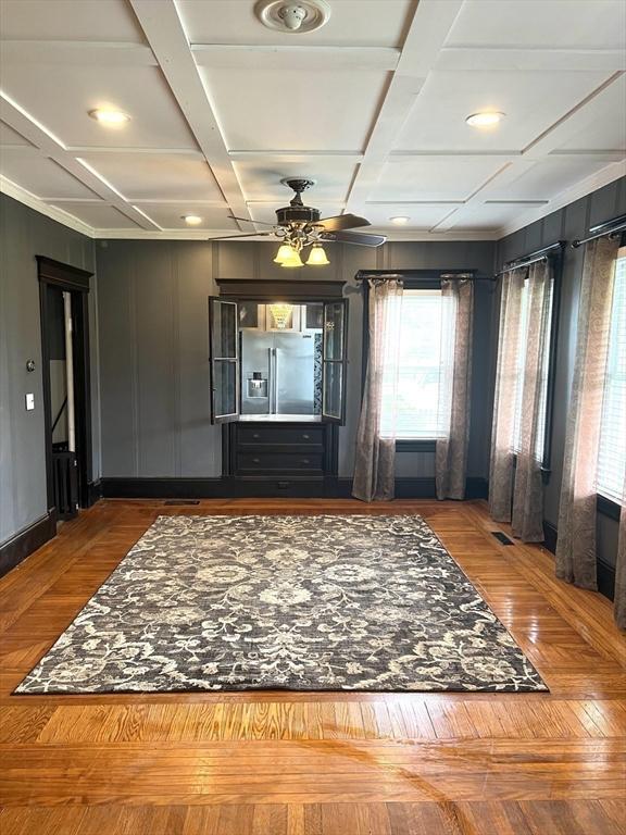 interior space with a ceiling fan, coffered ceiling, and visible vents