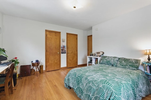 bedroom featuring light wood-style flooring, baseboards, and two closets