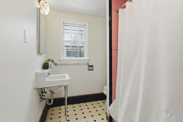 bathroom featuring toilet, tile patterned floors, baseboards, and a shower with shower curtain