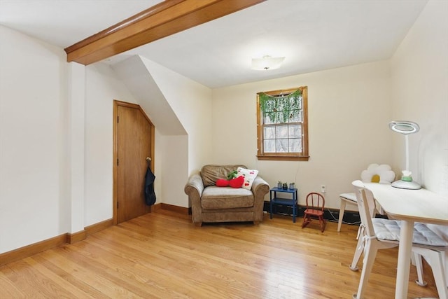 living area with light wood-type flooring, beam ceiling, and baseboards