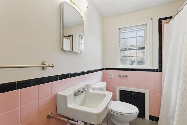 full bath with toilet, a sink, tile walls, and radiator heating unit