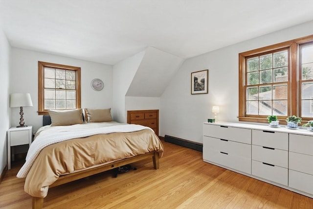 bedroom featuring vaulted ceiling, light wood finished floors, and multiple windows