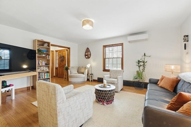 living area with a wall unit AC, baseboards, and wood finished floors