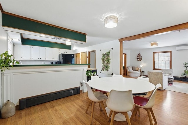 dining space with a baseboard heating unit, an AC wall unit, and light wood finished floors