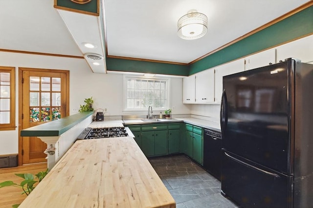 kitchen featuring stone finish flooring, white cabinetry, a sink, a peninsula, and black appliances