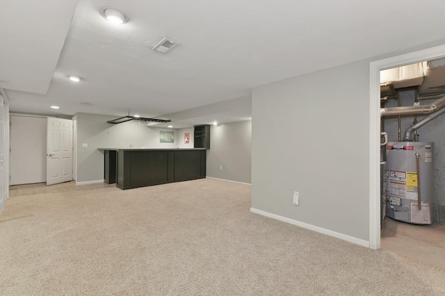 finished basement featuring gas water heater, light colored carpet, baseboards, and a bar