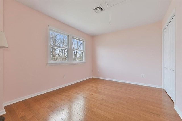 unfurnished bedroom with baseboards, light wood-style flooring, visible vents, and attic access