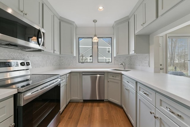 kitchen featuring stainless steel appliances, dark wood-style flooring, light countertops, and backsplash