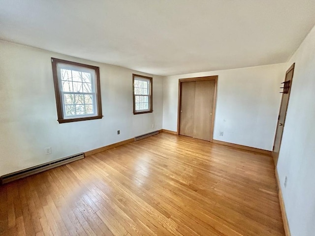 spare room featuring light wood-type flooring and baseboard heating