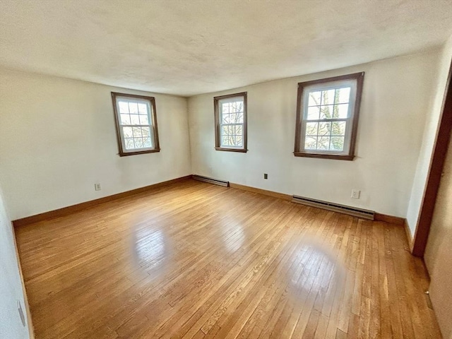 unfurnished room featuring light hardwood / wood-style floors, a baseboard radiator, and plenty of natural light