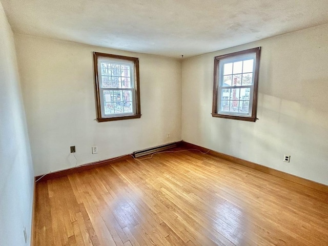 empty room with a baseboard heating unit and light wood-type flooring