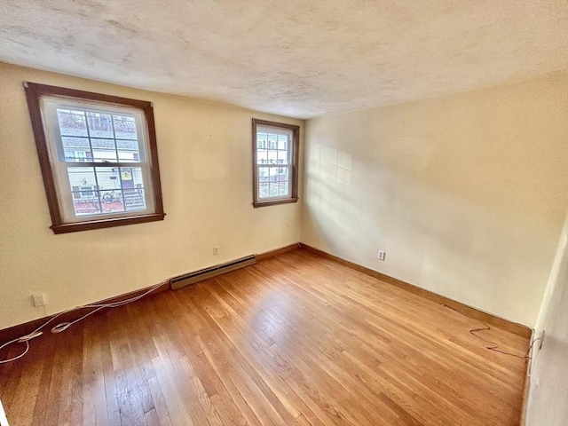 empty room with hardwood / wood-style flooring, a baseboard radiator, and a textured ceiling