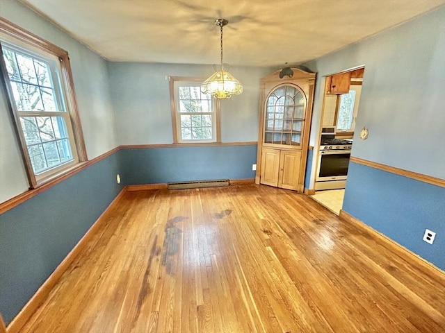 unfurnished dining area with light hardwood / wood-style floors, baseboard heating, and an inviting chandelier