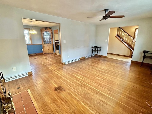 unfurnished room with a baseboard heating unit, ceiling fan with notable chandelier, and hardwood / wood-style flooring