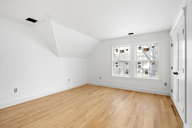 additional living space featuring vaulted ceiling and light wood-type flooring