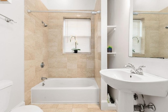 bathroom featuring tile patterned flooring, tiled shower / bath combo, and toilet