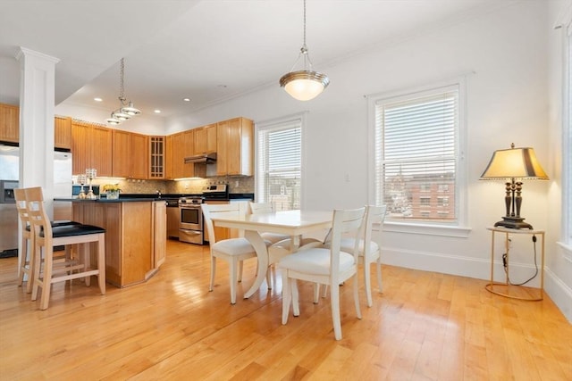 dining area featuring light hardwood / wood-style floors, ornamental molding, and a wealth of natural light