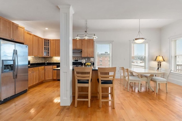 kitchen with backsplash, decorative columns, crown molding, decorative light fixtures, and appliances with stainless steel finishes