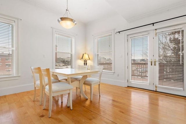 dining area featuring a healthy amount of sunlight, french doors, crown molding, and light hardwood / wood-style flooring