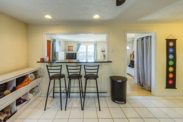 kitchen featuring a kitchen bar, light tile patterned floors, and kitchen peninsula