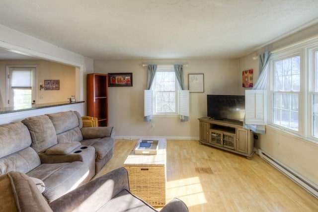 living room featuring a baseboard heating unit and light hardwood / wood-style flooring