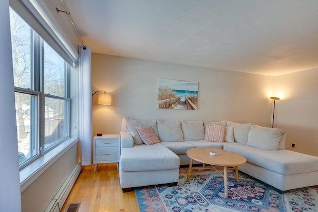 living room featuring a baseboard radiator, a healthy amount of sunlight, and light hardwood / wood-style floors