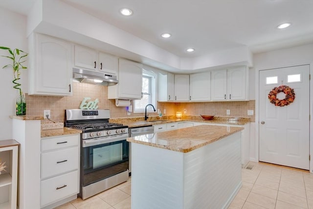 kitchen with a kitchen island, sink, white cabinets, stainless steel appliances, and light stone countertops