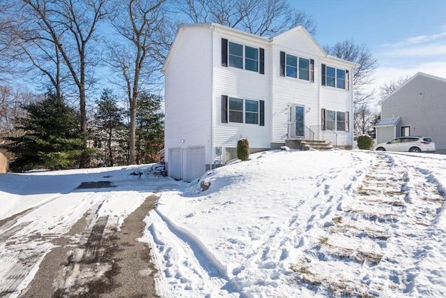 snow covered rear of property featuring a garage