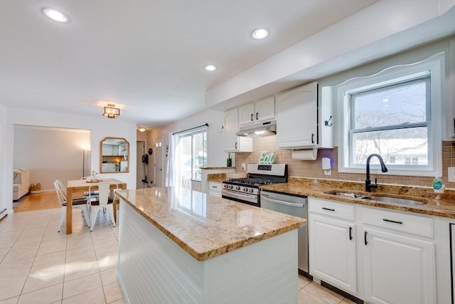 kitchen featuring sink, white cabinetry, light stone counters, a center island, and stainless steel appliances