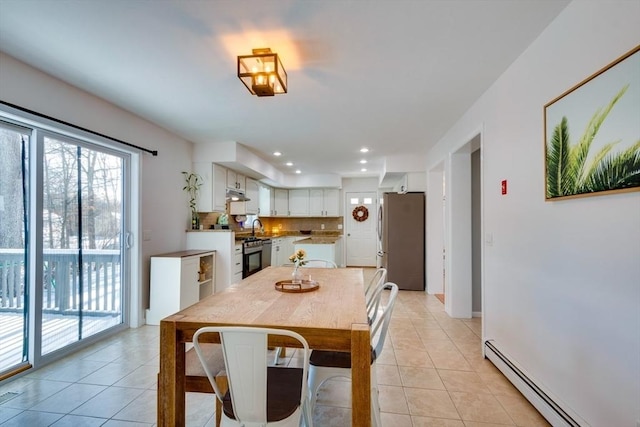 dining space featuring sink, a baseboard heating unit, and light tile patterned floors