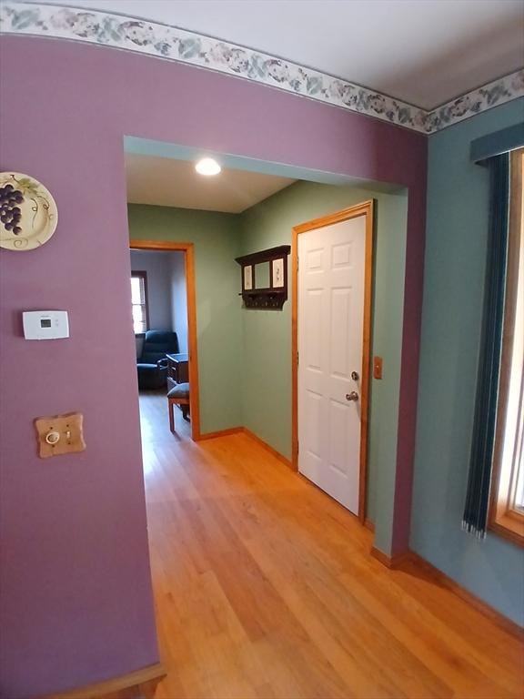 hall featuring light wood-style flooring and baseboards