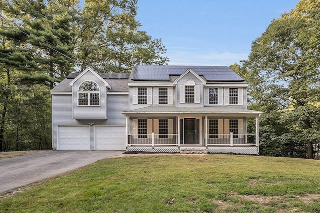 view of front of property with a porch, a garage, a front lawn, and solar panels