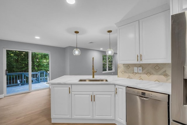 kitchen with white cabinetry, stainless steel appliances, kitchen peninsula, and sink