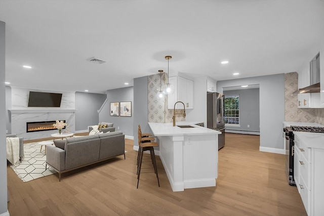 kitchen featuring decorative light fixtures, white cabinets, a kitchen breakfast bar, kitchen peninsula, and stainless steel appliances