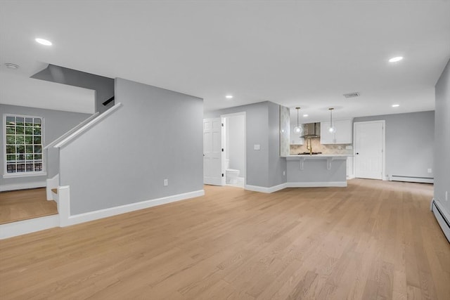 unfurnished living room featuring baseboard heating and light wood-type flooring