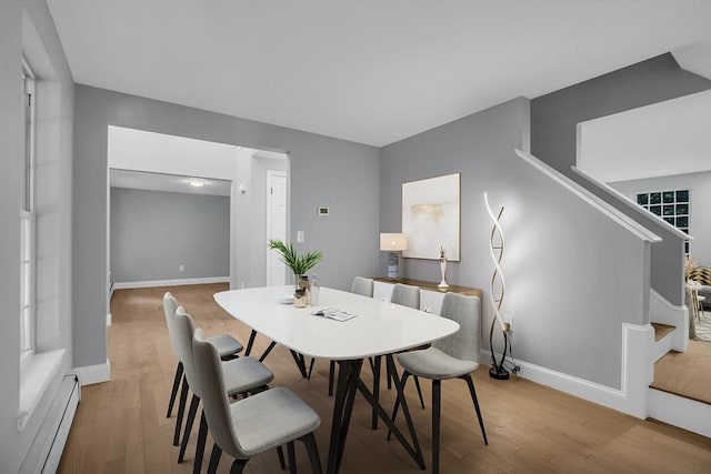 dining space with a baseboard heating unit and light hardwood / wood-style flooring