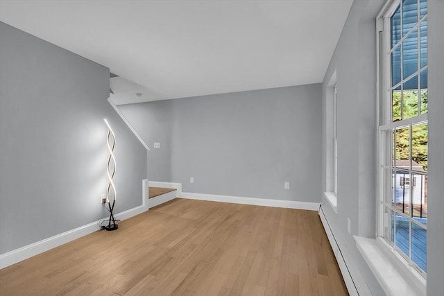 interior space with a baseboard heating unit and light hardwood / wood-style floors